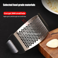 Stainless steel garlic press with black plastic handles.