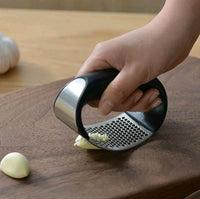 Stainless steel garlic press with rubber handles.