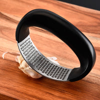 Stainless steel garlic press with rubber handles.