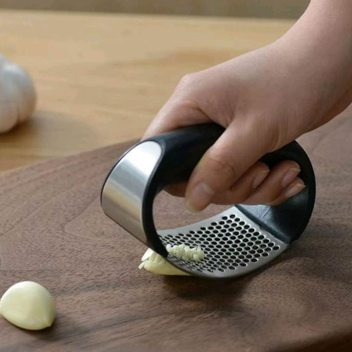 Stainless steel garlic press with rubber handles.