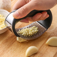 Stainless steel garlic press with black plastic handles.